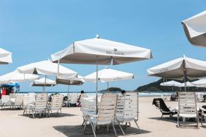 um monte de cadeiras e guarda-sóis numa praia em Pool Ilha da Madeira Resort em Riviera de São Lourenço