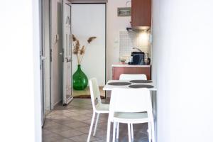 eine Küche mit einem Tisch und weißen Stühlen in der Unterkunft Daphne's studio 2 in Skiathos-Stadt