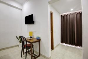 Habitación con escritorio y TV en la pared. en Niketan Medanta Service Apartment - A BOUTIQUE HOTEL en Gurgaon