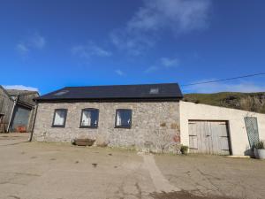 un antiguo edificio de piedra con techo negro en The Old Parlour en Rhyl