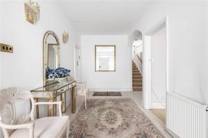 a white hallway with a table and chairs and a mirror at Large 5 Bedroom house in Finchley in Maida Vale