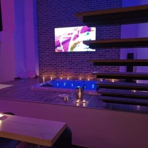 a room with a tub with a tv on a wall at magnifique loft avec jacuzzi et sauna privatif in Ferrière-la-Grande