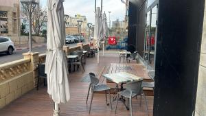 a row of tables and chairs with white umbrellas on a sidewalk at Margoa Hotel Netanya in Netanya