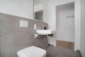 y baño con aseo blanco y lavamanos. en Moderne Apartments im Herzen von Osnabrück I private Tiefgarage I home2share, en Osnabrück