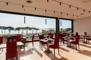 a restaurant with tables and chairs and large windows at HA Hotel in Bracciano