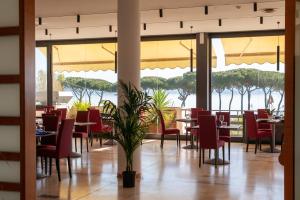 ein Restaurant mit Tischen und Stühlen und Blick auf das Wasser in der Unterkunft HA Hotel in Bracciano
