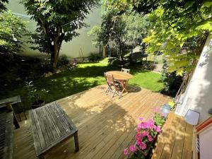 a wooden deck with a table and a bench at Appartement Cosy avec Jardin in Saint-Cloud
