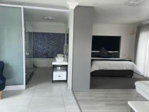 Le Rubis Guesthouse في Van Riebeekhoogte: غرفة نوم مع سرير وحوض استحمام في غرفة