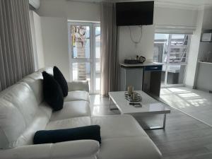 Le Rubis Guesthouse في Van Riebeekhoogte: غرفة معيشة مع أريكة بيضاء وطاولة