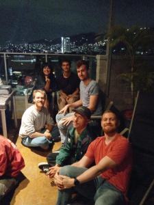 a group of people sitting on a rooftop at night at Hostel Metro Floresta Alojamiento in Medellín
