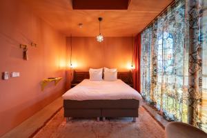 a bedroom with a bed and a large window at Boutiquehotel The Church in Arnhem