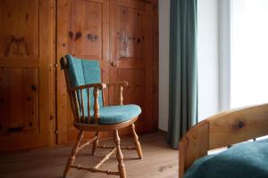 uma cadeira de balanço em madeira num quarto com uma cama em Alpenhaus Montafon em Gargellen