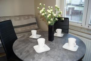 een tafel met een vaas met witte bloemen erop bij Pokoje gościnne przy Kochanowskiego in Mielno