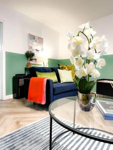 a living room with a blue couch and a vase with white flowers at Cwtch Corner By MGroup SA in Treherbert