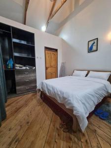 1 dormitorio con 1 cama grande y suelo de madera en Kichaka Cottages en Nyeri
