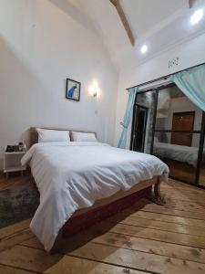 a bedroom with a large white bed with a window at Kichaka Cottages in Nyeri
