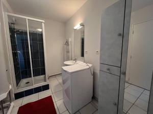 een witte badkamer met een wastafel en een douche bij Appartement T3 Duplex Saint Cast Le Guildo in LʼIsle-Saint-Cast