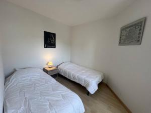 een slaapkamer met 2 bedden en een tafel met een lamp bij Appartement T3 Duplex Saint Cast Le Guildo in LʼIsle-Saint-Cast