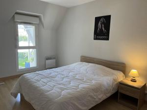 1 dormitorio con cama blanca y ventana en Appartement T3 Duplex Saint Cast Le Guildo en LʼIsle-Saint-Cast