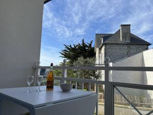 een tafel met wijnglazen en een fles op een balkon bij Appartement T3 Duplex Saint Cast Le Guildo in LʼIsle-Saint-Cast