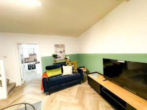 a living room with a blue couch and a large flat screen tv at Cwtch Corner By MGroup SA in Treherbert