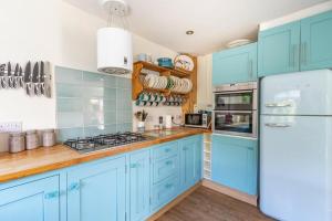 a blue kitchen with blue cabinets and a refrigerator at Sea View Cottage Southwold in Southwold