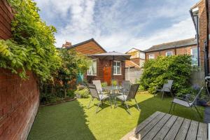 a patio with a table and chairs and an umbrella at Sea View Cottage Southwold in Southwold