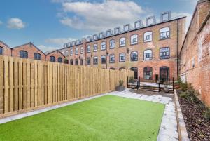 a garden in front of a brick building with a wooden fence at Modern 1 Bedroom Apartment Near Nottingham Train Station in Nottingham