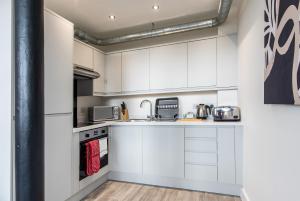 a white kitchen with white cabinets and appliances at Modern 1 Bedroom Apartment Near Nottingham Train Station in Nottingham