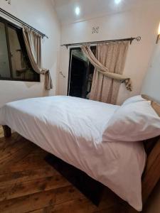 a bedroom with a large white bed and a window at Kichaka Cottages in Nyeri