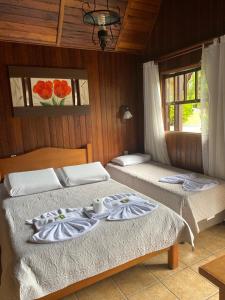 duas camas num quarto com duas janelas em Pousada Serras De Monte Verde em Monte Verde
