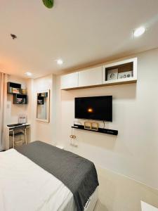 a bedroom with a bed and a flat screen tv on the wall at Primo Condo Studio Type - One Pontefino Tower in Batangas City