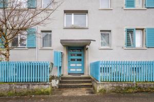 a blue fence in front of a house with a blue door at Apartment in the heart of Oerlikon in Zurich