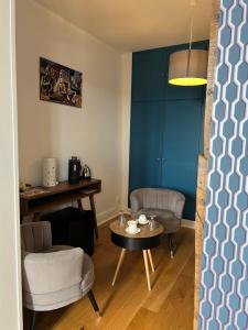 sala de estar con mesa, sillas y pared azul en Le Clos d 'Aÿ, en Épernay