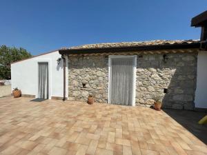 ein Haus mit einer Steinmauer und einer Terrasse in der Unterkunft La casa degli ulivi in Centuripe