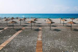 a group of umbrellas on a beach with the ocean at Hotel Olymp Pervaya Liniya in Adler