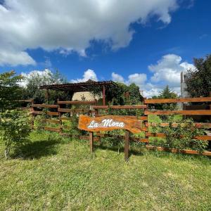 eine Holzbank im Gras neben einem Zaun in der Unterkunft La Mora Cabañas in Villa Urquiza