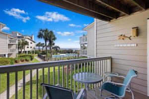 a balcony with a table and chairs and a view of a pool at 8A Seagrove Villa in Isle of Palms