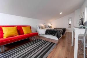Un dormitorio con una cama y un sofá rojo. en Praça Velha II - Estúdio no Centro de Braga, en Braga