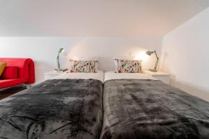 1 dormitorio con 2 camas y silla roja en Praça Velha II - Estúdio no Centro de Braga, en Braga