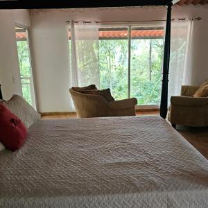 a bedroom with a bed and two chairs and windows at OLP Treehouse Cerro Azul in Cerro Azul