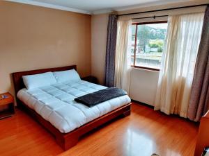 a bedroom with a large bed with a window at Casa Quirola hermosa y muy grande in Cuenca