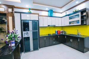 eine Küche mit einem Kühlschrank und Holzschränken in der Unterkunft Villa Ngọc Trai - NT75 FLC Sầm Sơn in Sầm Sơn