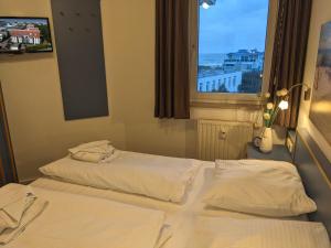 two beds in a hotel room with a window at Yachthafenresidenz-Wohnung-8404-866 in Kühlungsborn