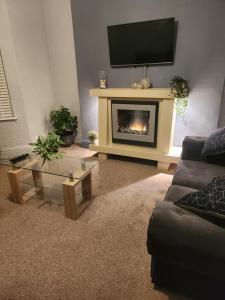 a living room with a fireplace with a tv above it at CHERRYTREE COTTAGE @ LOMOND in Hornsea