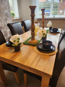 a wooden table with plates and bowls on it at CHERRYTREE COTTAGE @ LOMOND in Hornsea