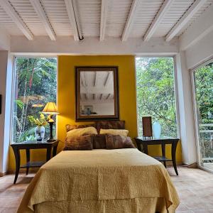 een slaapkamer met een bed met een gele muur bij OLP Treehouse Cerro Azul in Cerro Azul