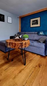 a living room with a blue couch and a wooden table at Myśliwska chata Staś i Nel in Bystrzyca Kłodzka