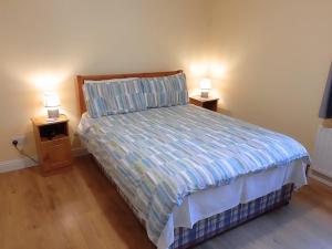 a bedroom with a bed and two night stands with lamps at Robins Roost Cornamona in Cornamona