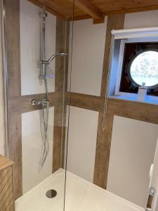 a glass shower in a bathroom with a window at Péniche Le Pescalune - Chambre d'hôtes in Arles